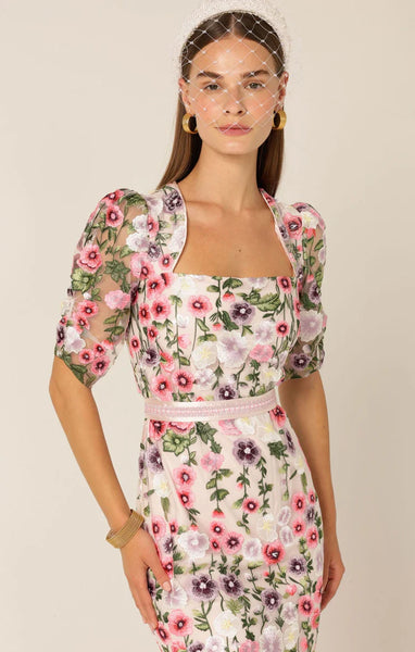Woman wearing a floral dress with puff sleeves against a beige Sacha Drake - Alyssium Midi Dress - Pink Lilac Floralbackground