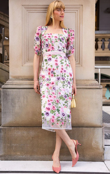 Woman in a floral dress standing against a stone wall. Sacha Drake - Alyssium Midi Dress - Pink Lilac Floral